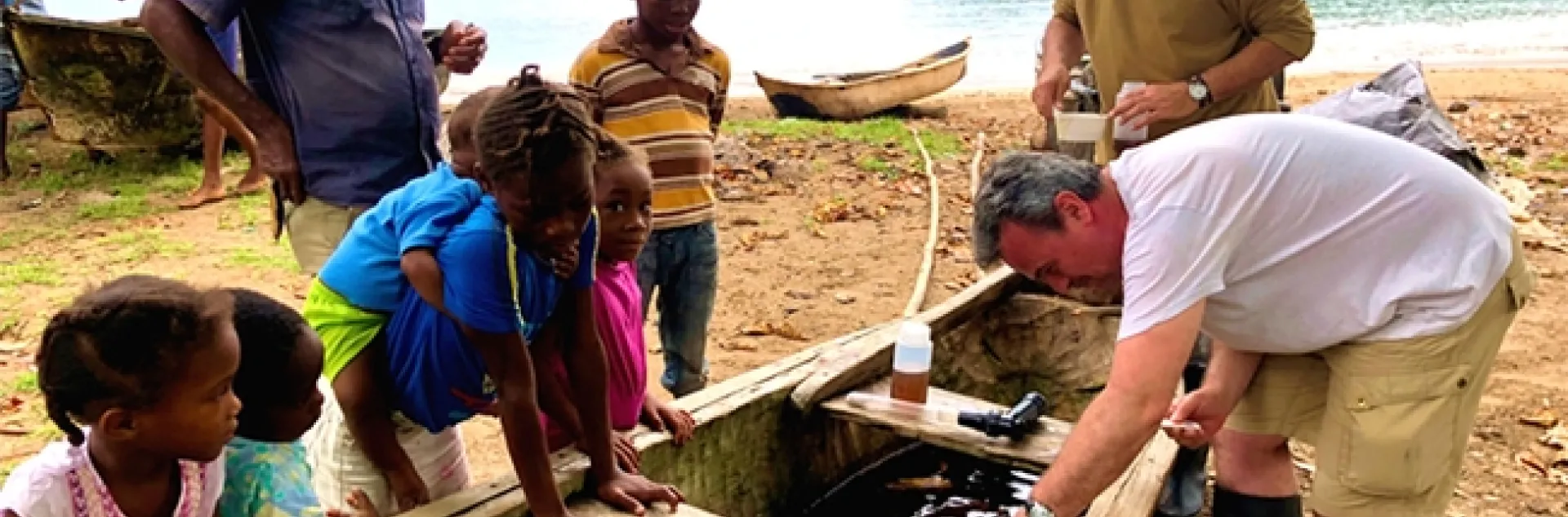 Neighborhood children watch as Institute of Hygiene and Tropical Medicine team members Greg Lanzaro (top) of UC Davis and João Pinto of the Institute of Hygiene and Tropical Medicine, Lisbon, Portugal, collect mosquito samples.