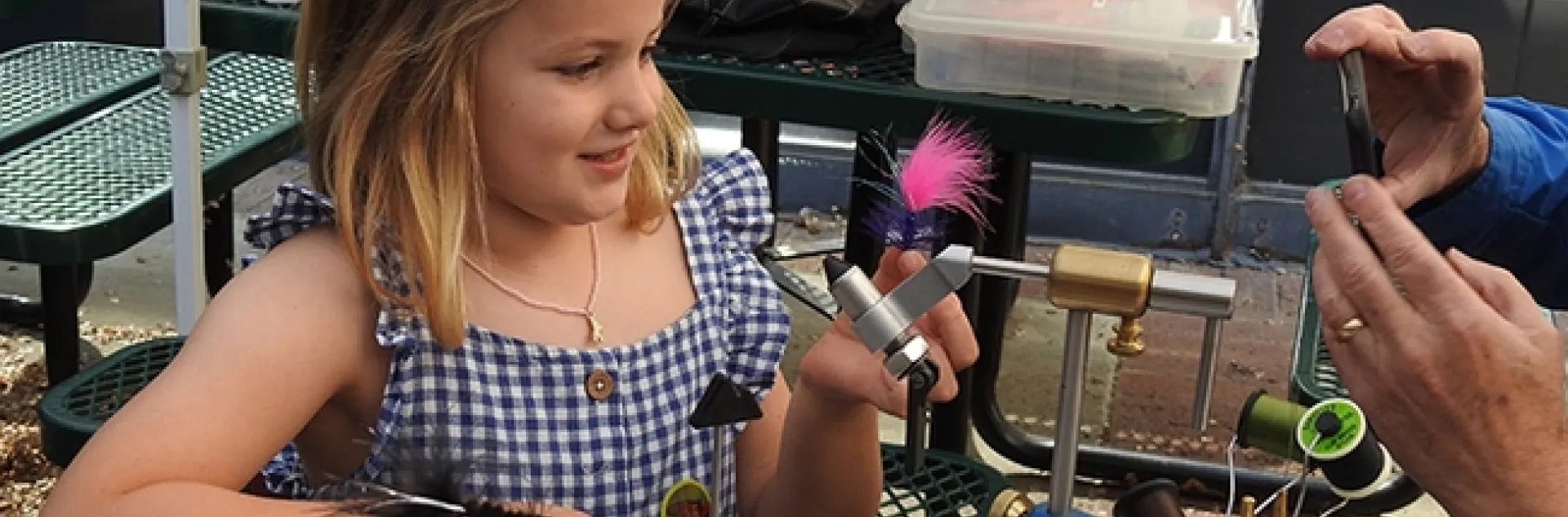 Ella Eich proudly displays the pink fly created by Paul Berliner of the Fly Fishers of Davis. (Photo by Kathy Keatley Garvey)