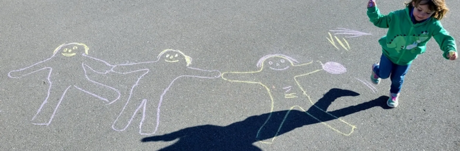 A girl plays among chalk figures drawn on pavement.