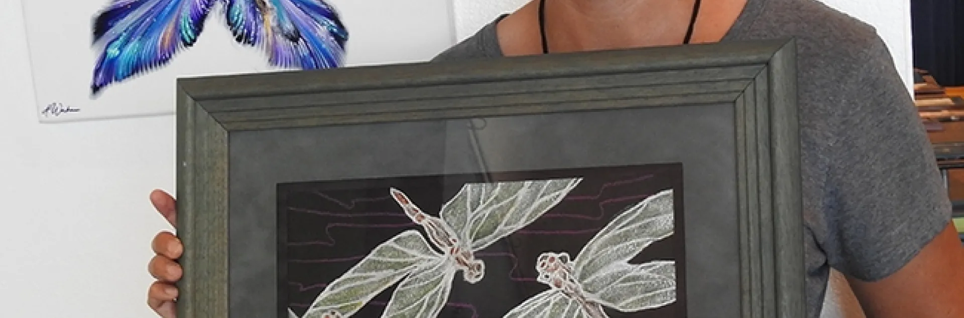 Heather DeGroot of Vallejo, coordinator of the McCormack Hall exhibits, Solano County Fair, shows a watercolor by Richard Laswell of Rio Vista that depicts three dragonflies. In back is an oils-acrylic butterfly by Ashley Workman of Vallejo. (Photo by Kathy Keatley Garvey)