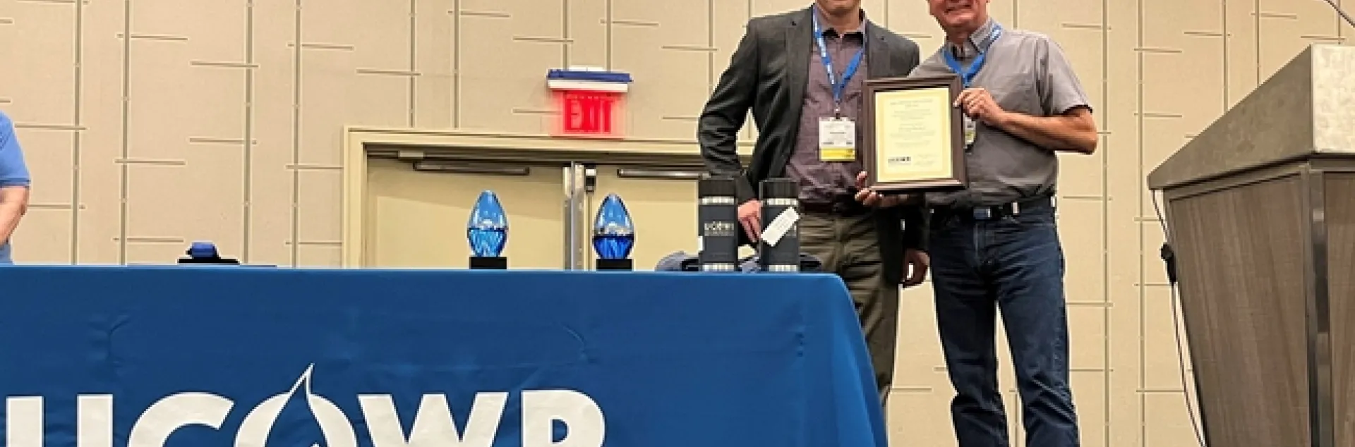Two men standing on stage with plaque.