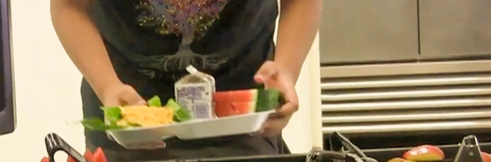 En la foto se aprecia a un estudiante tomando alimentos en una bandeja.