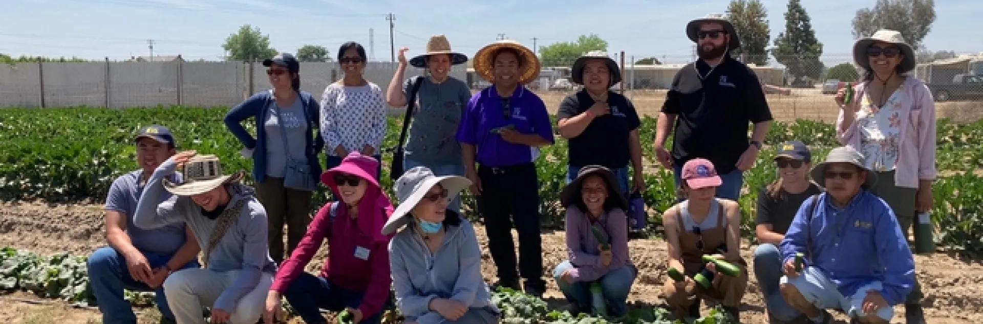 The UC Cooperative Extension small farms team poses among leafy greens at a Hmong farmer's farm.