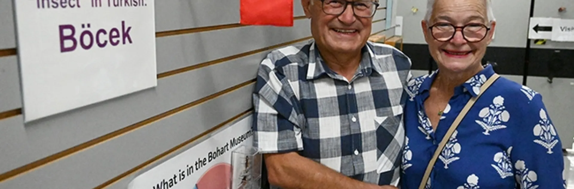 At the Bohart Museum of Entomology, Dr. Ismail Seker and his wife, Esin, stand in front of the Turkish flag and a card indicating how to say "insect" in the Turkish language. The Bohart Museum spotlights a global collection of flags, as well as how to say "insect" in many languages. (Photo by Kathy Keatley Garvey)
