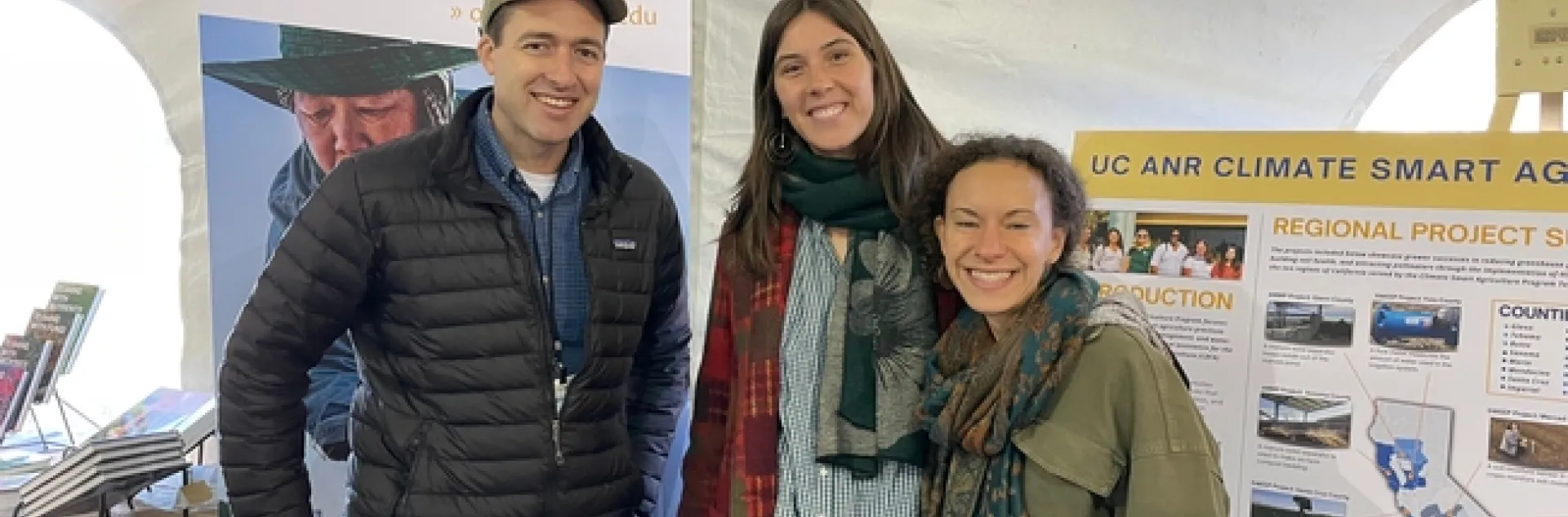 OAI representatives stand in front of posters about the Organic Agriculture Institute and climate-smart agriculture