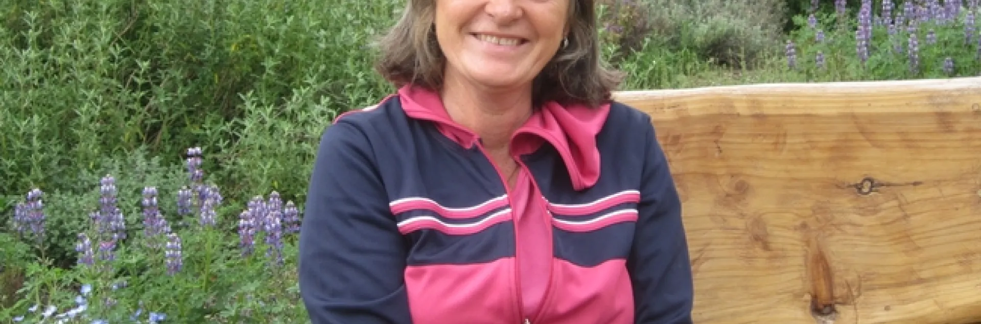 Author sitting on bench with a background of wildflowers.
