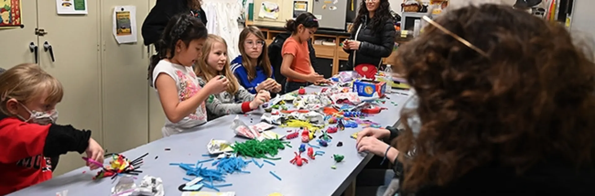 With UC Davis students (right) assisting at the Bohart Museum arts-and-crafts table, artists create arthropods and other critters, using modeling clay. (Photo by Kathy Keatley Garvey)