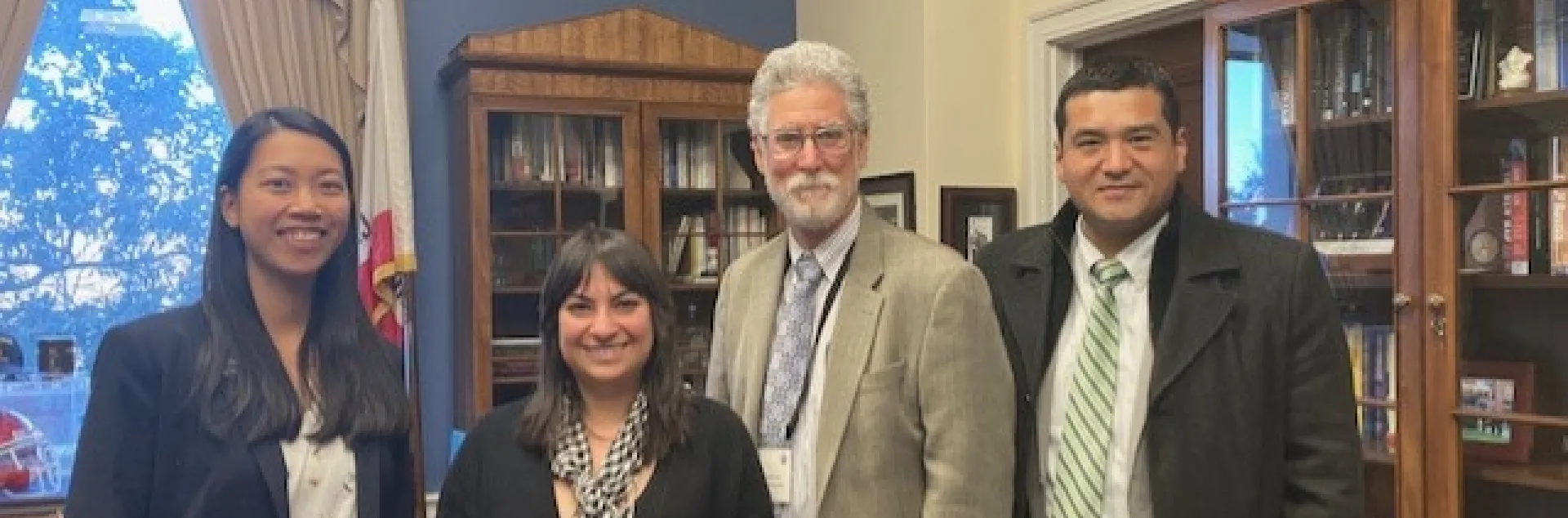 The four people stand together in a congressional office.