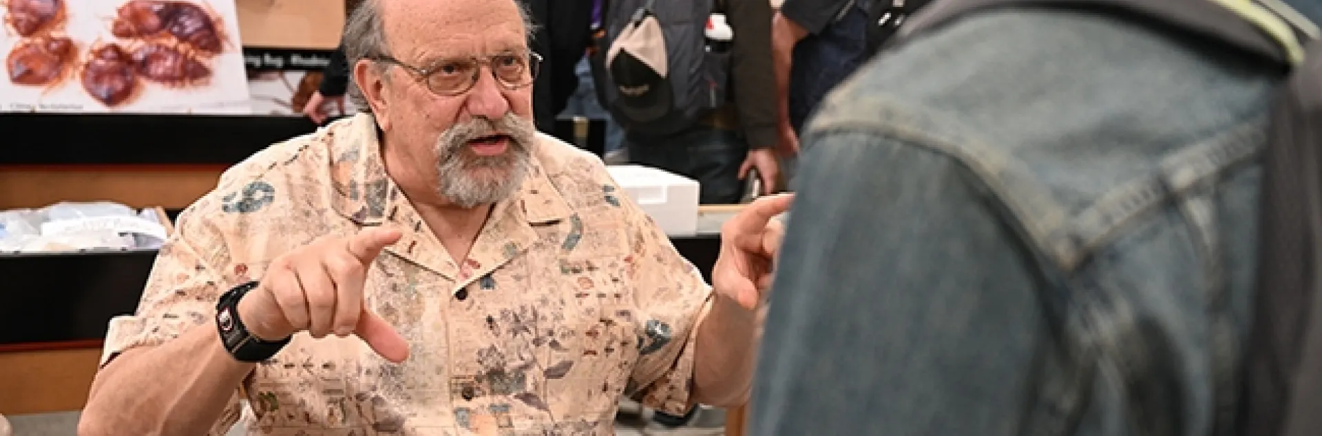 UC Davis forensic entomologist Robert "Bob" Kimsey explains his research. In back is a graphic of bed bugs. (Photo by Kathy Keatley Garvey)
