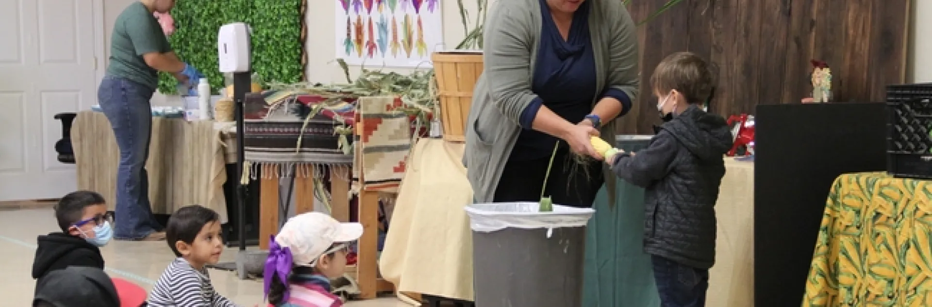 Pies de grabado Stacey Amparano ayuda a sus jóvenes voluntarios a desgranar una mazorca.