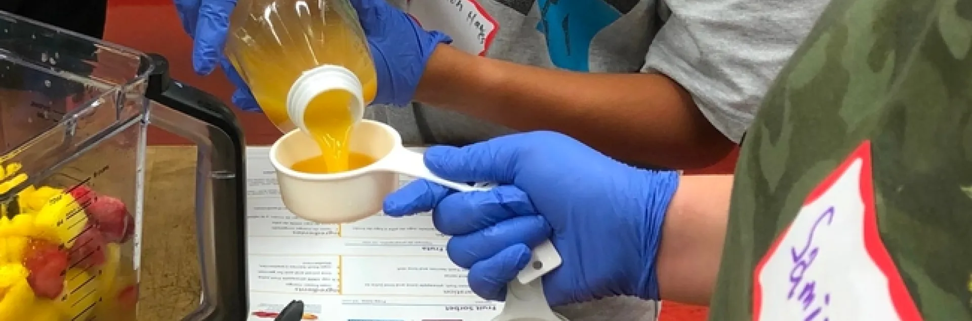 Un estudiante de Teens Love Cooking (Los adolescentes aman cocinar) miden ingredientes para hacer un batido.