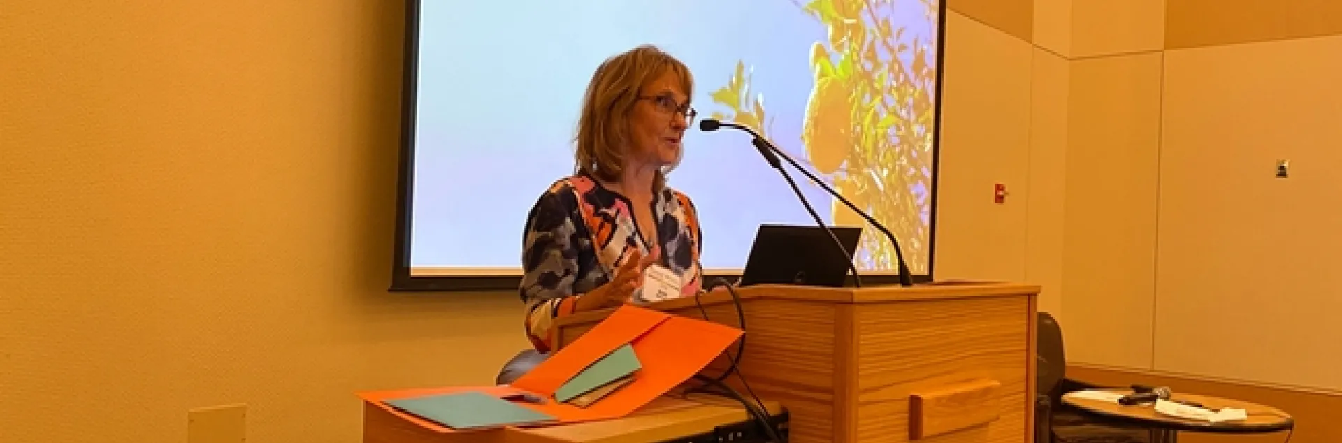 Beth speaking at a lectern. Slide behind her reads "Postharvest Center."