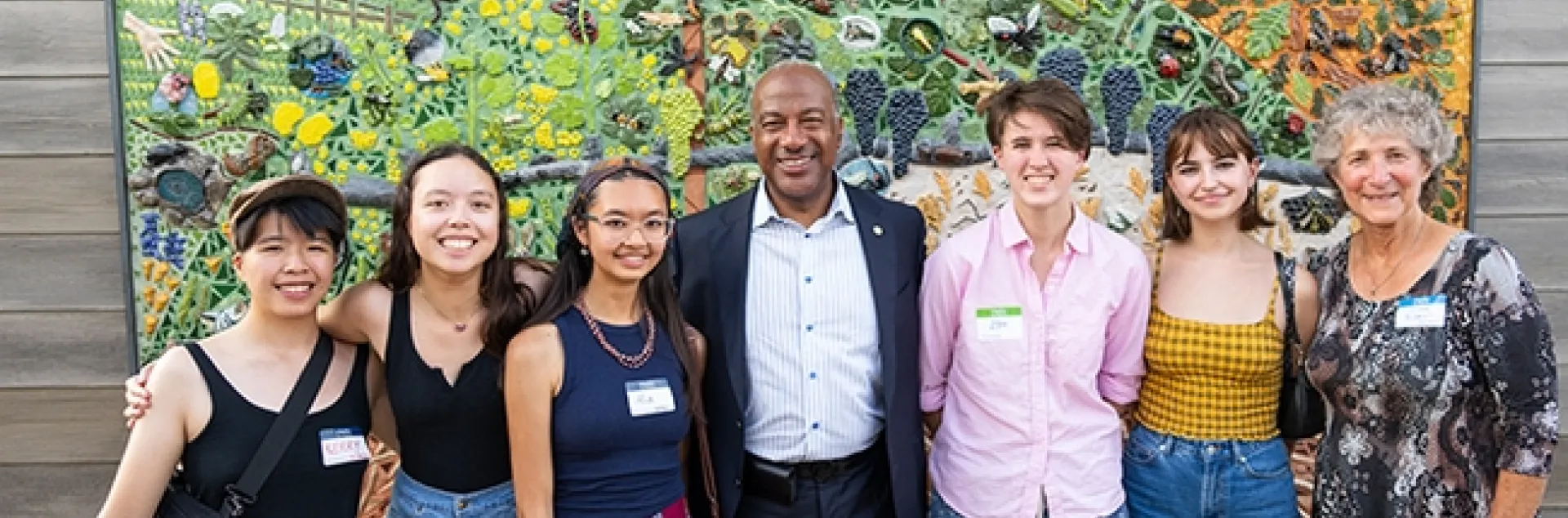 Posing for a celebratory photo are five mural participants with Chancellor Gary May and UC Davis distinguished professor Diane Ullman. From left are Kerry Lin, Sierra Deaver, Alia Tu, Chancellor May, Zoe Meilandt, Lily Nugent and Professor Ullman. (Photo courtesy of Jael Mackendorf, UC Davis College of Agricultural and Environmental Sciences)