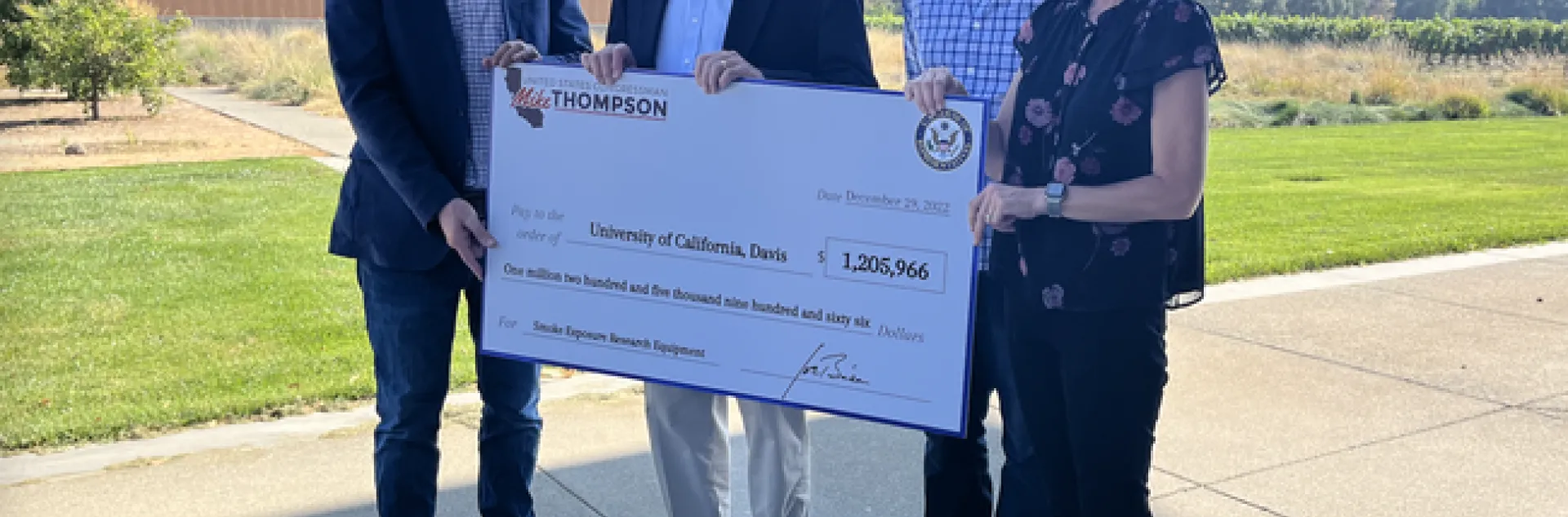 Four people hold a large ceremonial check for $1,205,966.