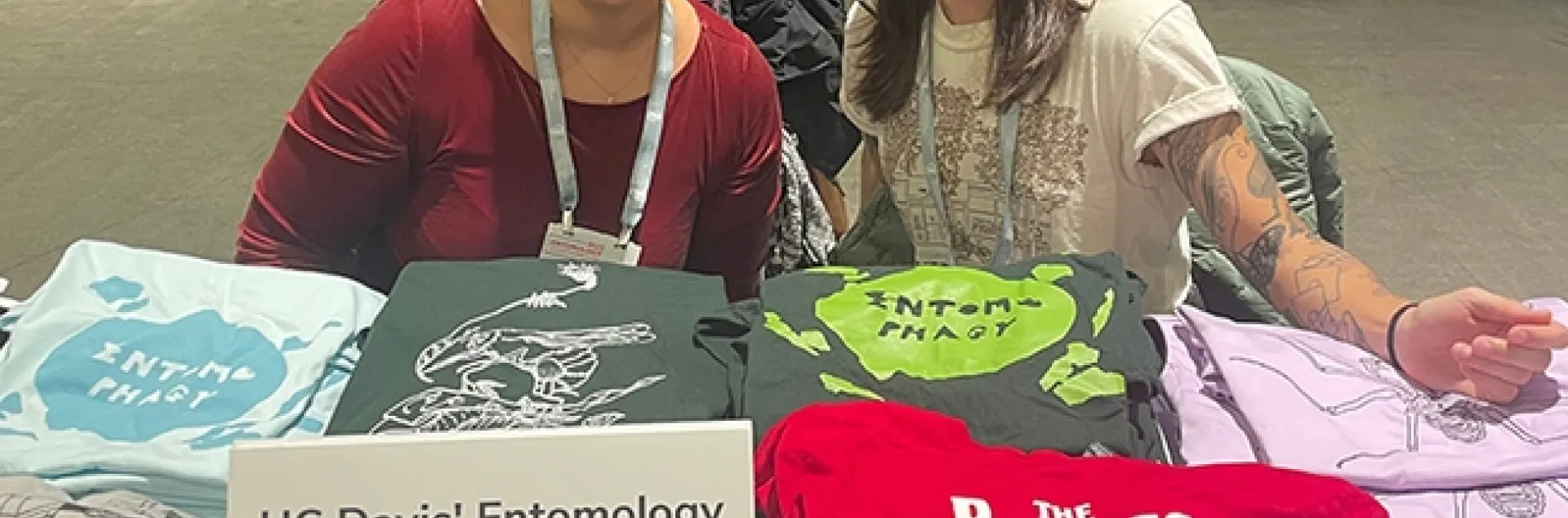 UC Davis doctoral students Iris Quayle (left) of the Jason Bond lab and Mia Lippey of the labs of UC Davis distinguished professor Jay Rosenheim and assistant professor Emily Meineke, show some of the EGSA T-shirts. Lippey serves as EGSA president, and Quayle as treasurer.