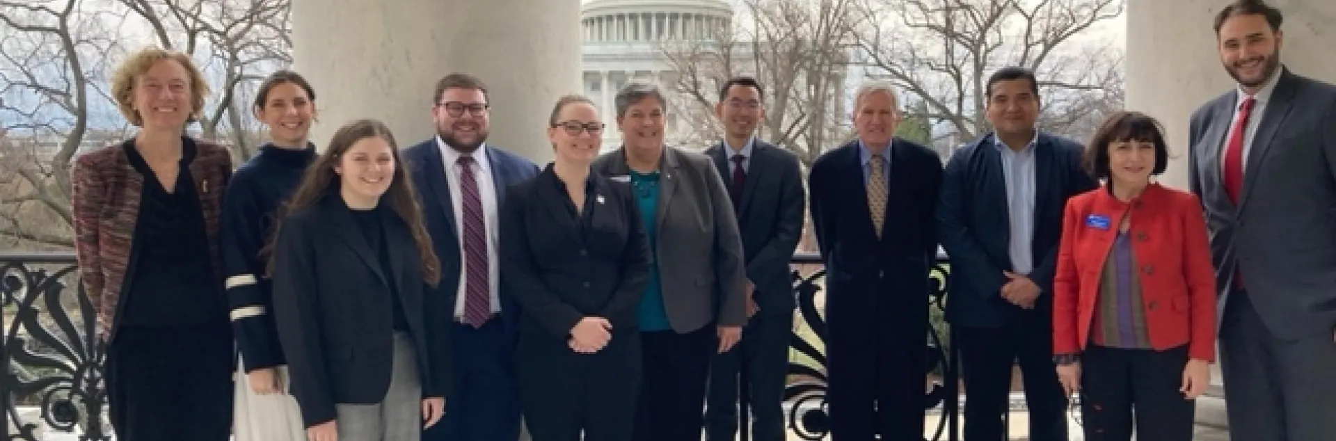 Group of people stand with U.S. capitol in the background.