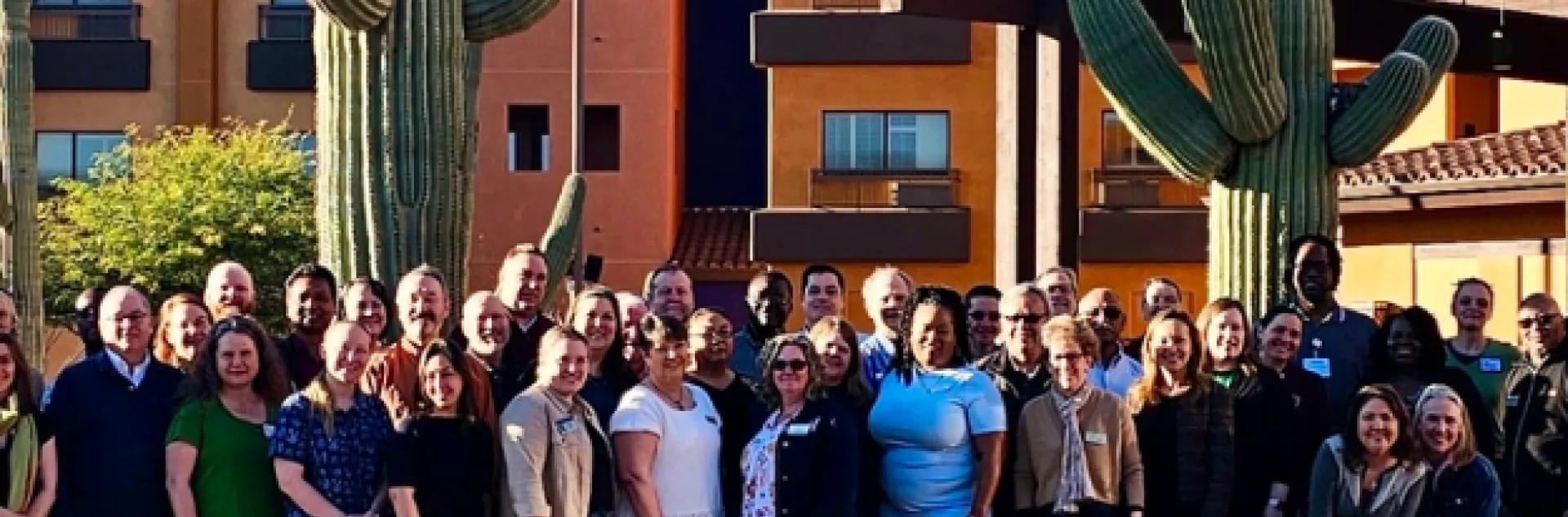 Group of people flanked by two large saguaro cacti.