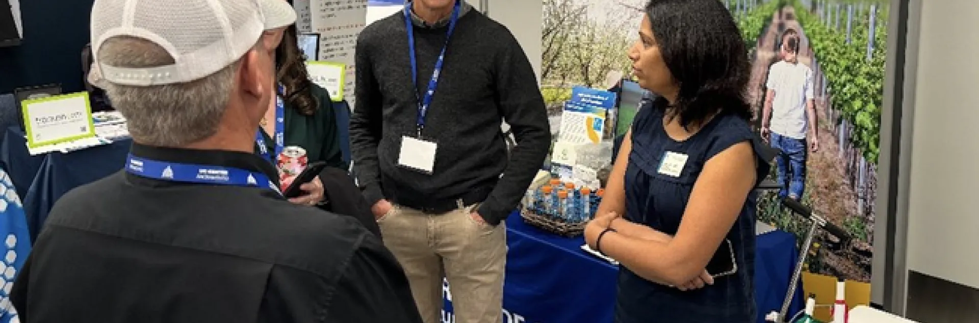 Four people stand and converse at a display booth