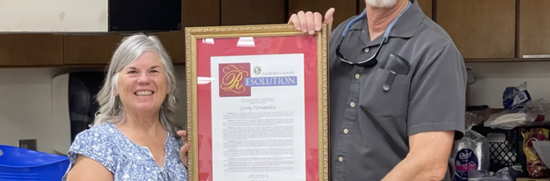Gerry and Franz stand holding opposite sides of the large, framed document.