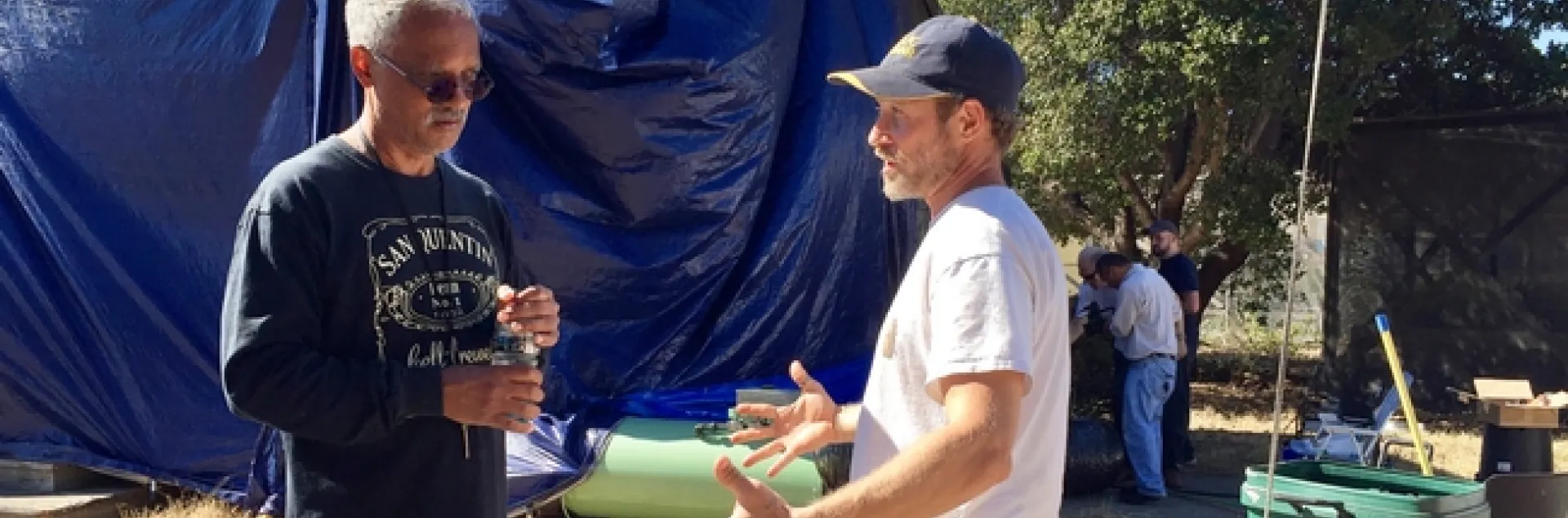 Lewis and Sutherland stand in front of a tarped structure