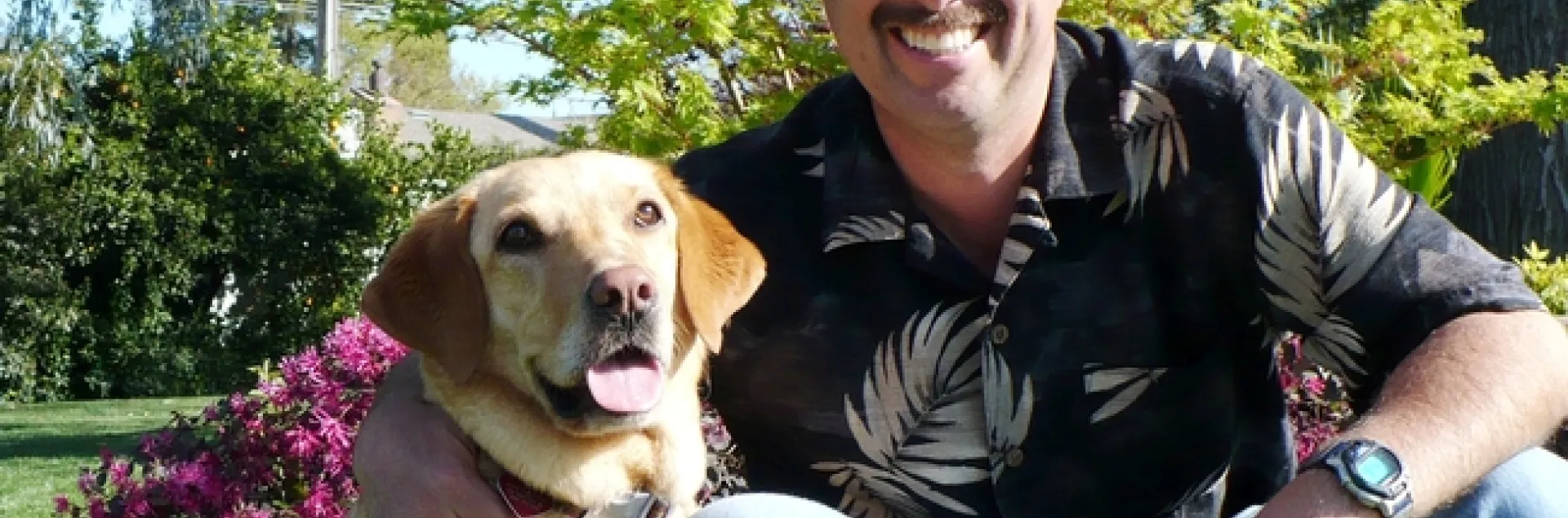 Roger sits beside his dog, a golden lab.