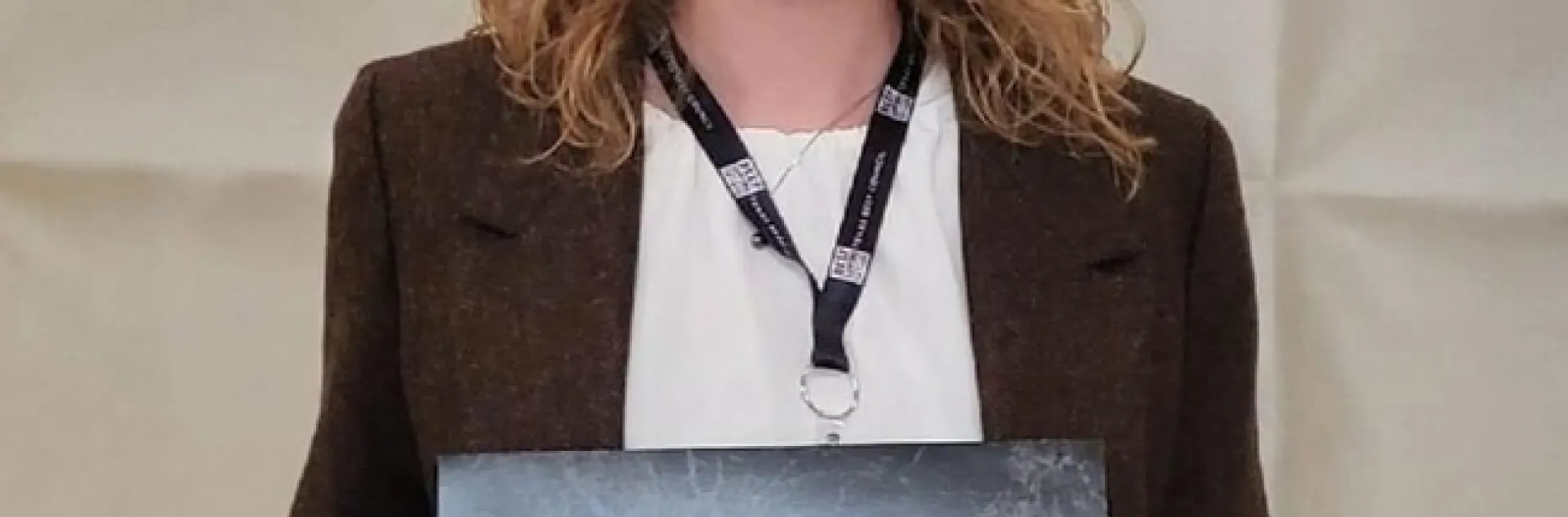 Laura Snell holds a plaque with the logo of the National Association of County Agricultural Agents.