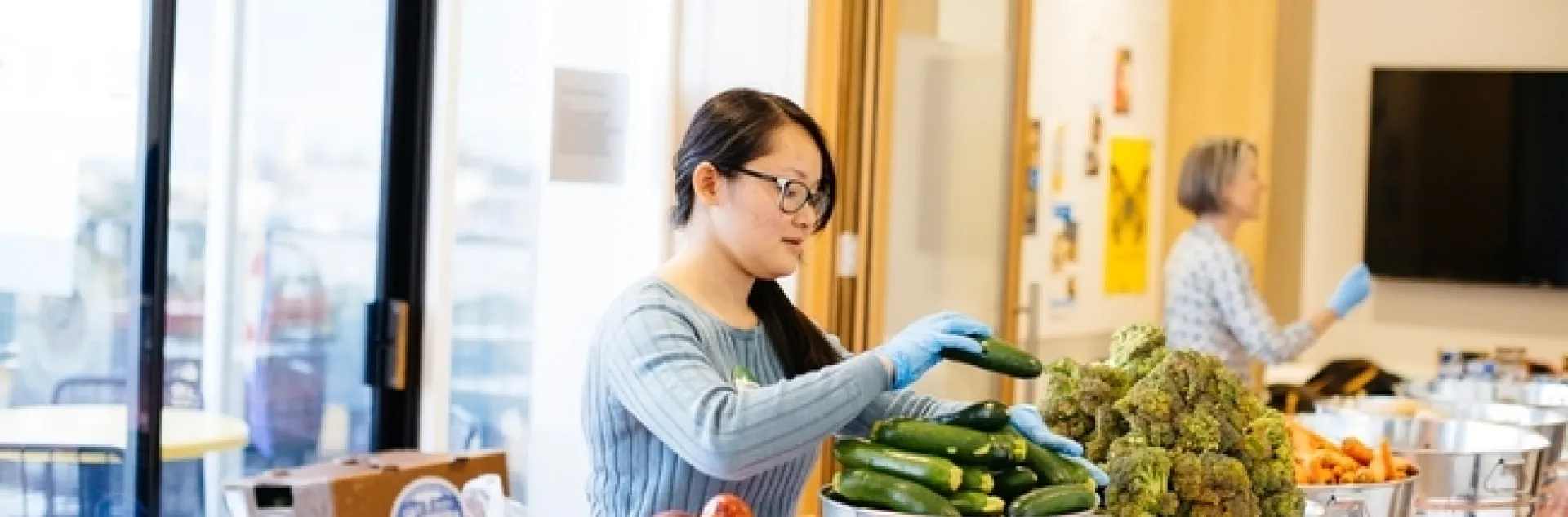 Una mujer en una mesa con distintos vegetales.