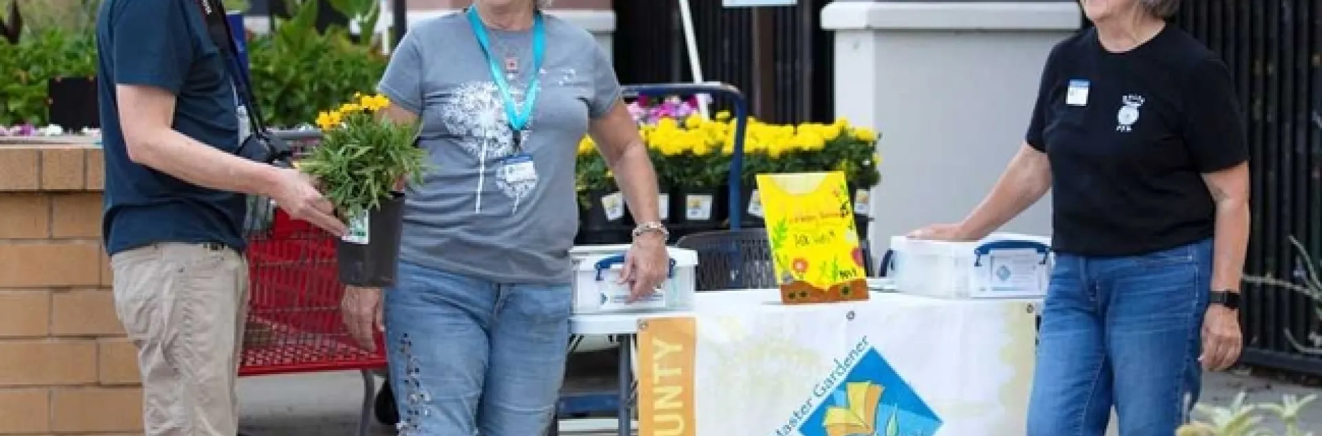 People talking in front of a UC Master Gardener Table at a garden store