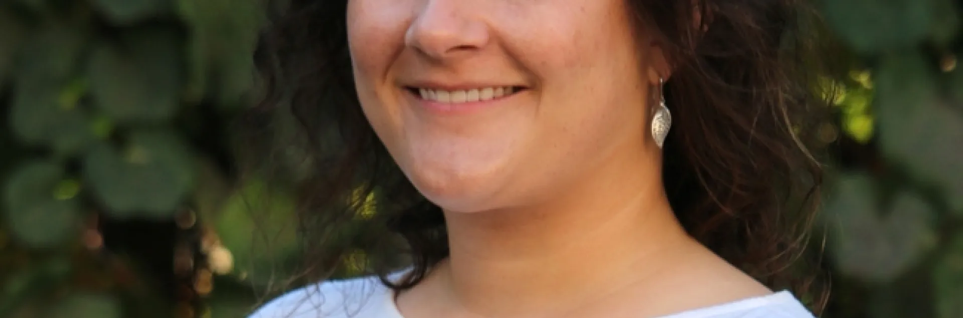 Headshot of woman with brown hair in a white top.