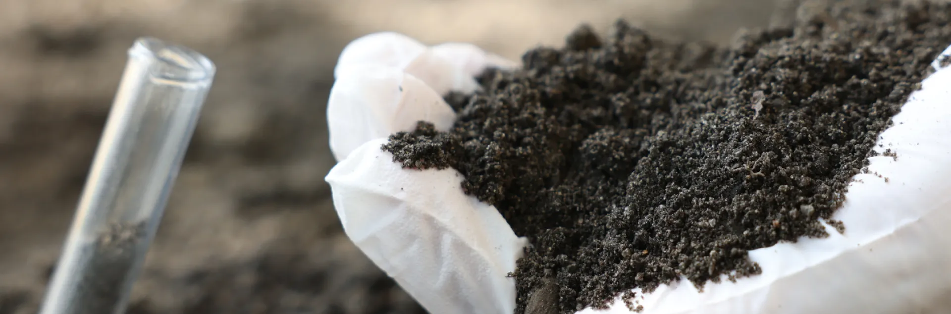 close up of hand holding soil with test tube of soil 
