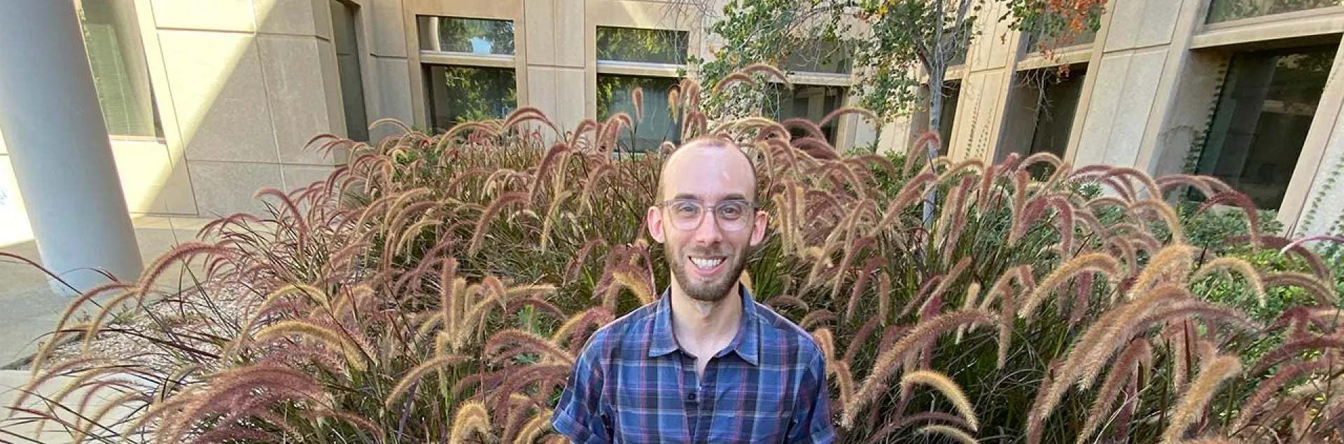 Justin stands outdoors among landscape plants