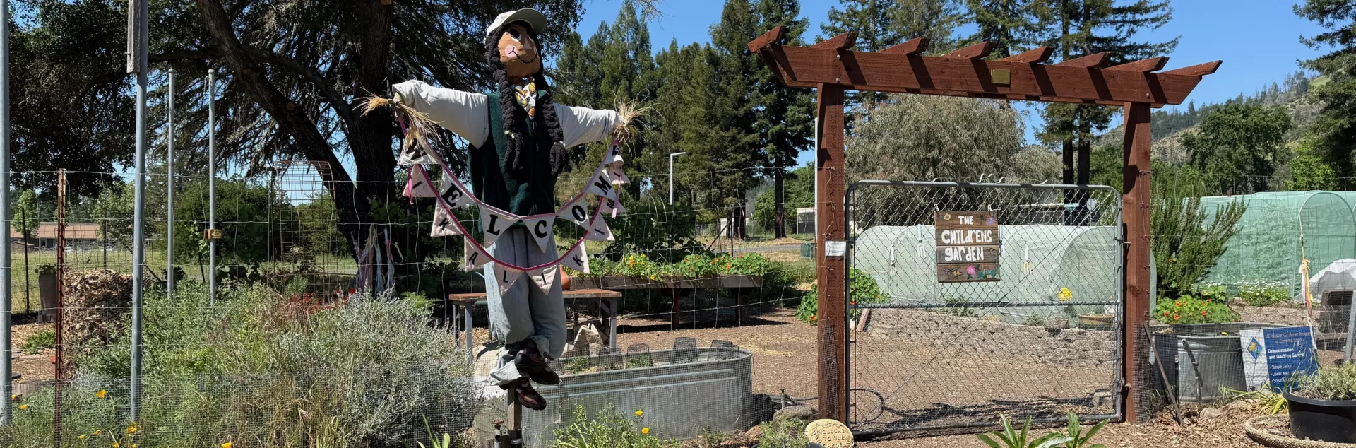 Front gate to a children's garden with a scarecrow in the foreground