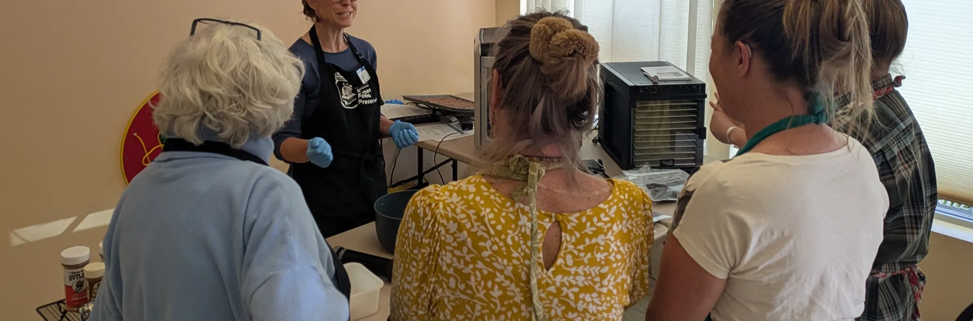 A group of adult watching another adult demonstrating jerky making.