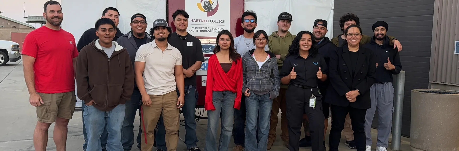 A farm robotics team stands in front of a backdrop that reads Hartnell College
