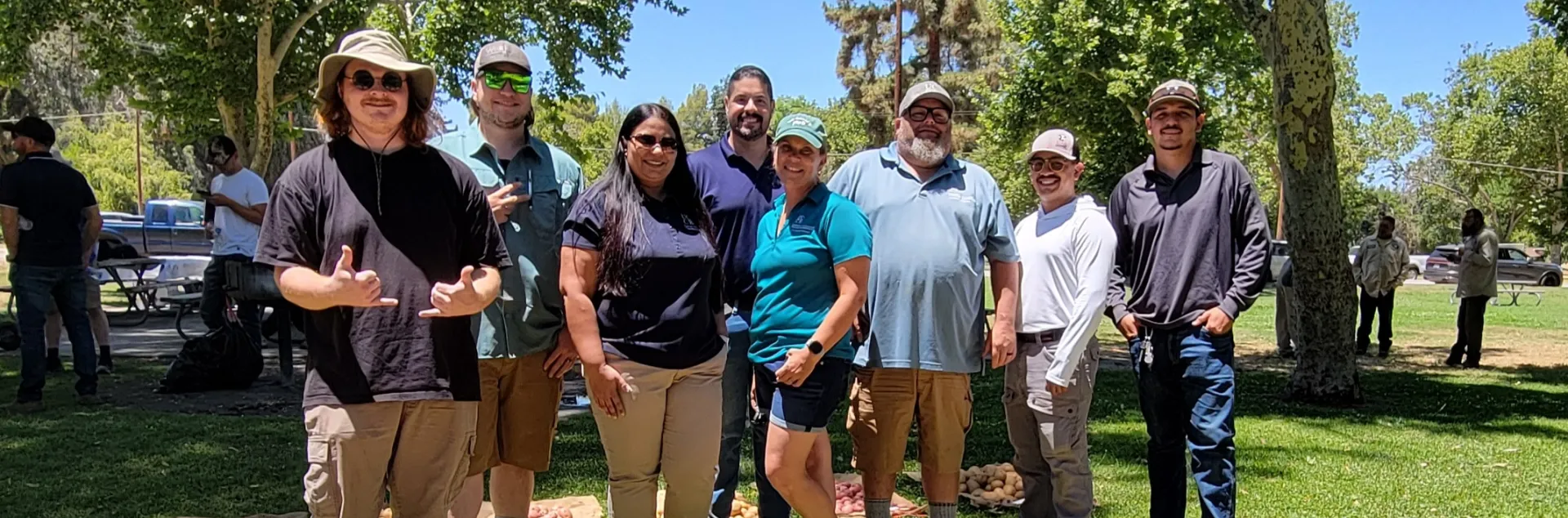 Leonel Jimenez (center) smiles with the potato variety trial team as potatoes are displayed on burlap sacks on the grass