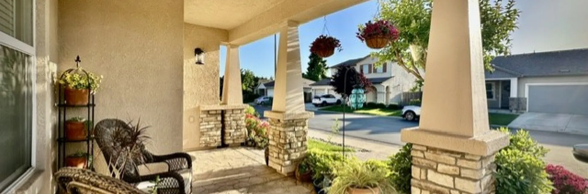 Picture of a suburban front porch with green landscaping and outdoor furniture arranged on the porch.