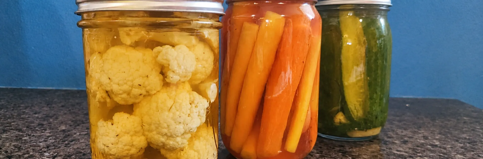 three jars containing pickled vegetables