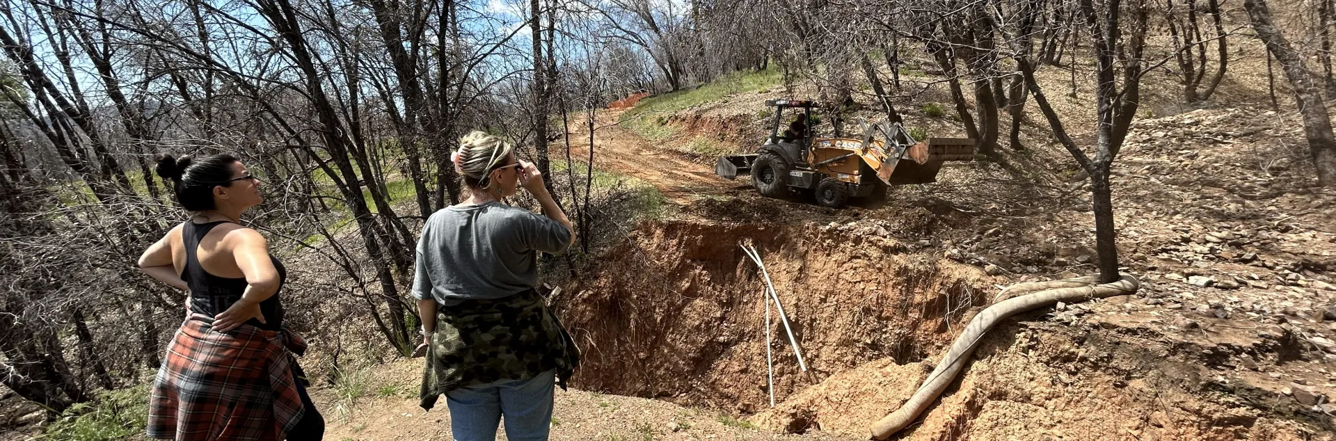 Two people examine erosion damage on a forest road.