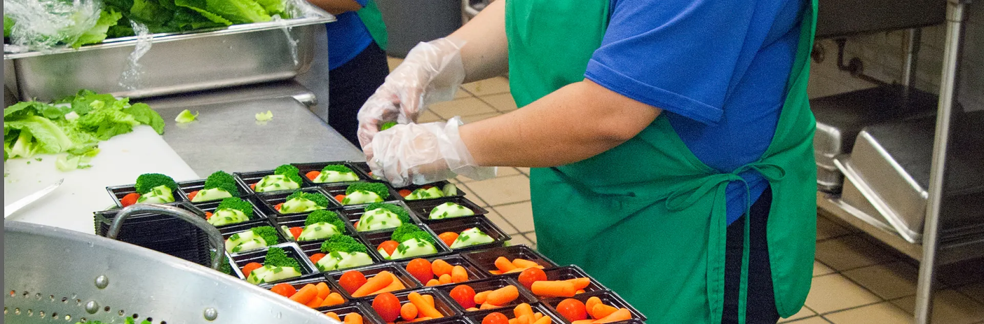 Food service staff preparing healthy school meals in a school kitchen.