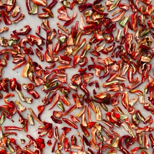 Sliced red peppers dehydrated on parchment paper.