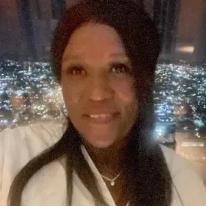 headshot of a woman standing in front of a cityscape at night