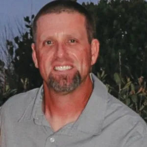 man with light brown hair wearing a grey shirt