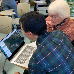 A man and a woman work in front of a computer.