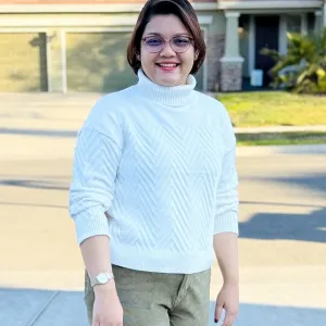 woman standing with baby blue top on and brunette hair