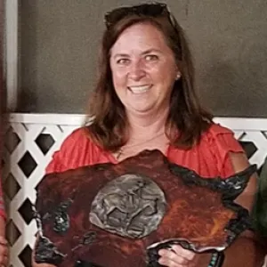 Brunette woman holding a wooden award from calpac