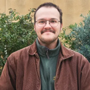 male with brown jacket and glasses