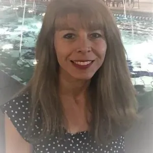 woman with medium length brown hair and bangs wearing a black shirt with white polka dots