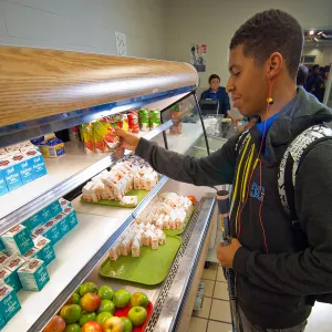 A high school student grabs a pre-made meal from the school cafeteria lunch line.
