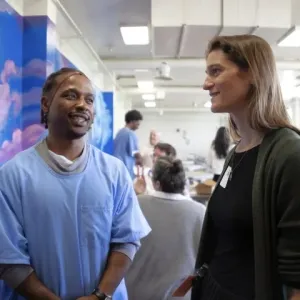 A farmer speaks with an incarcerated individual wearing a hair net.