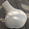 A close-up of a garlic bulb with a smooth white exterior resting on a wooden surface.